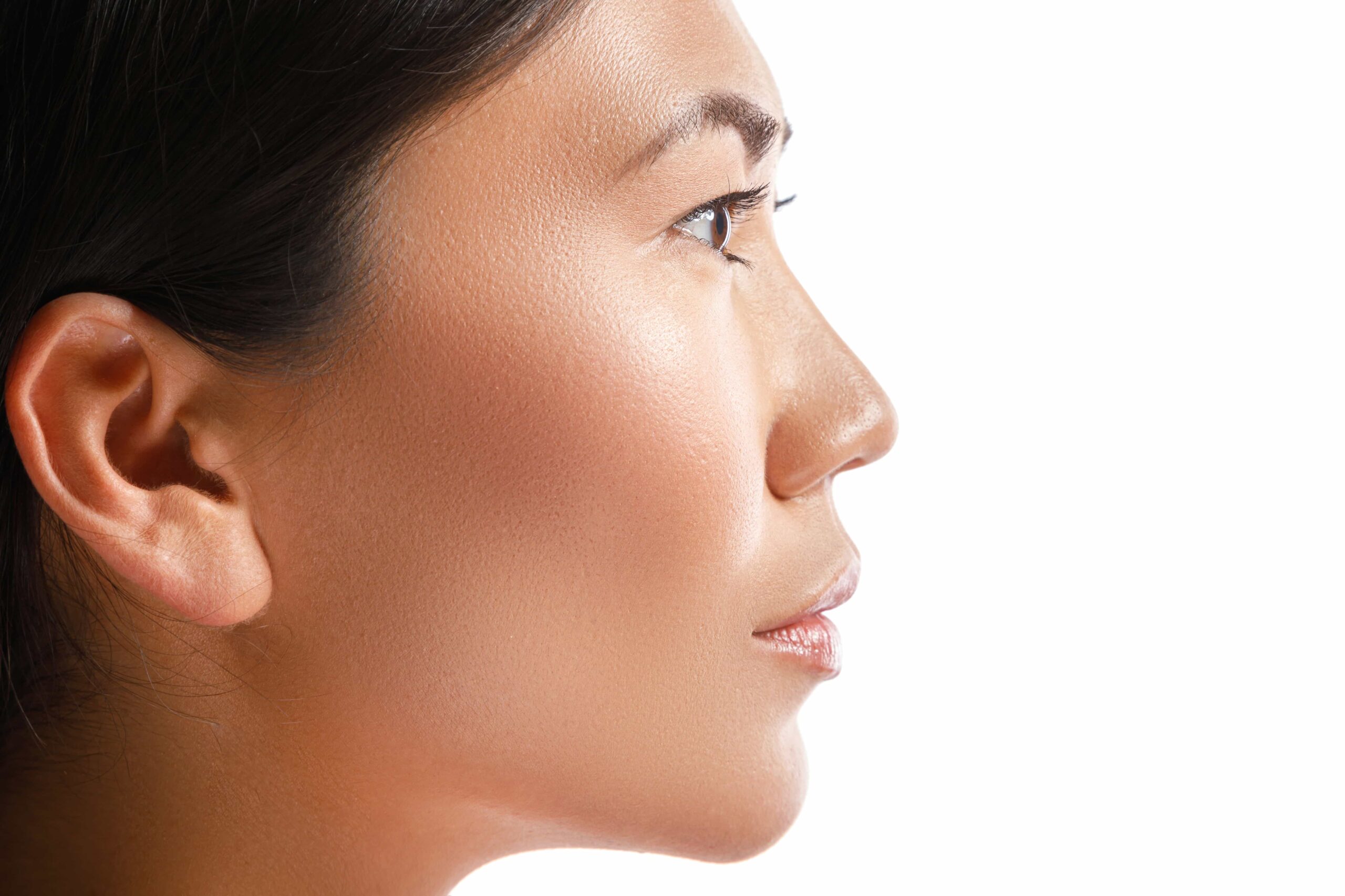 Side profile close-up of a woman's face highlighting the smooth contour of her nose, cheek, and jawline against a white background.