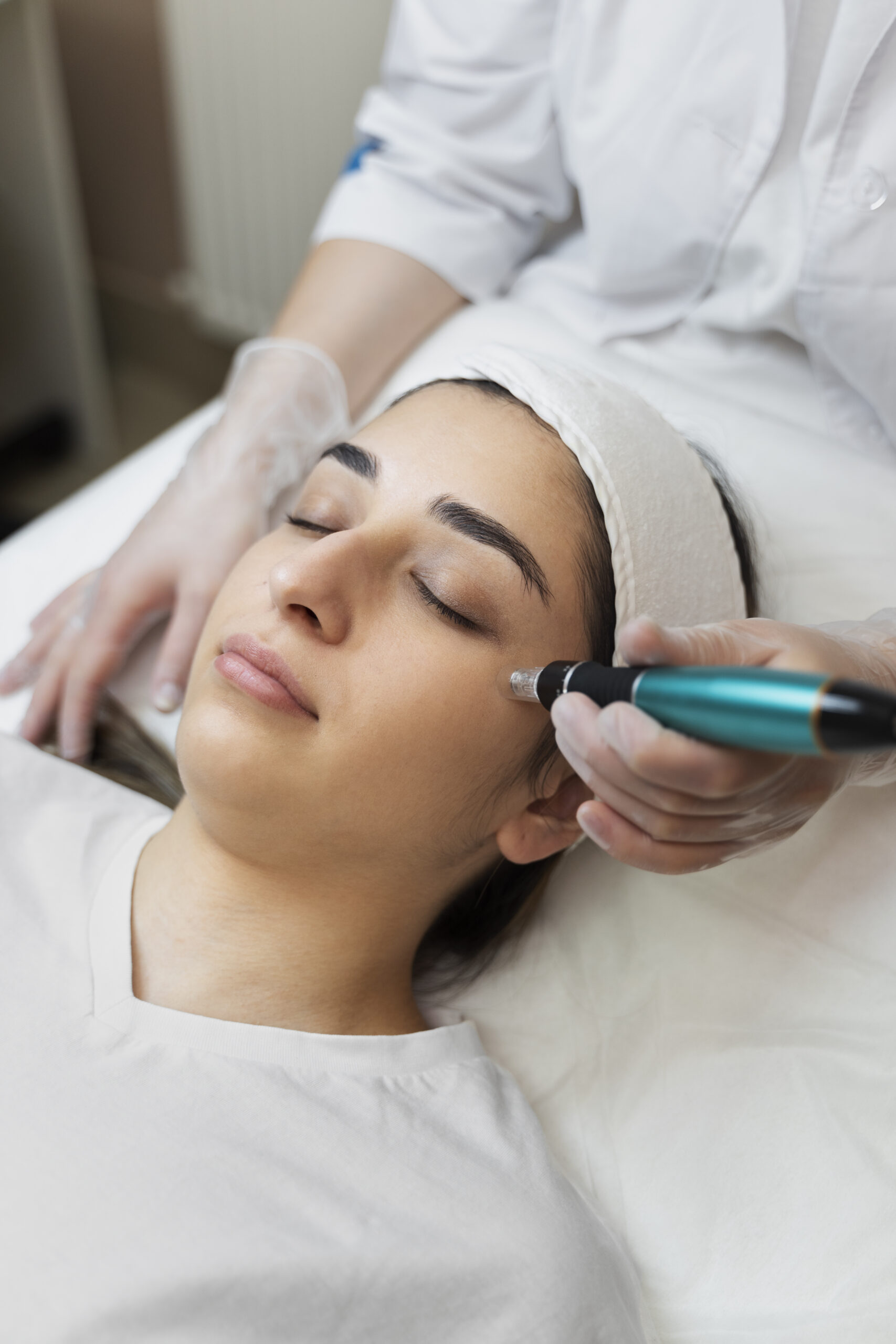 Detailed close-up of a client receiving a skin treatment with a dermapen device targeting the area near her cheekbone.