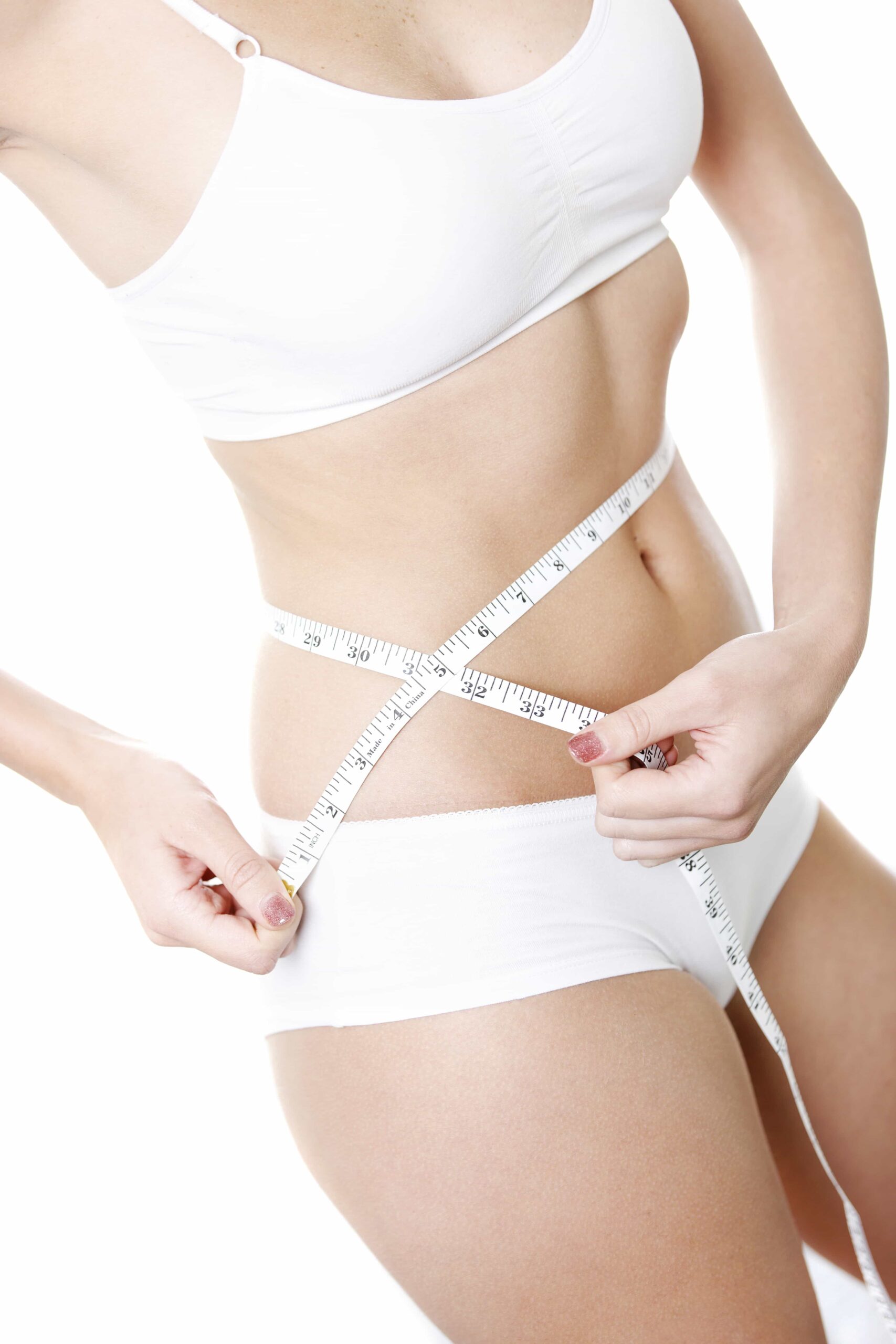Close-up of a woman in white underwear wrapping a measuring tape around her slim waist, highlighting body contouring and fat reduction results.