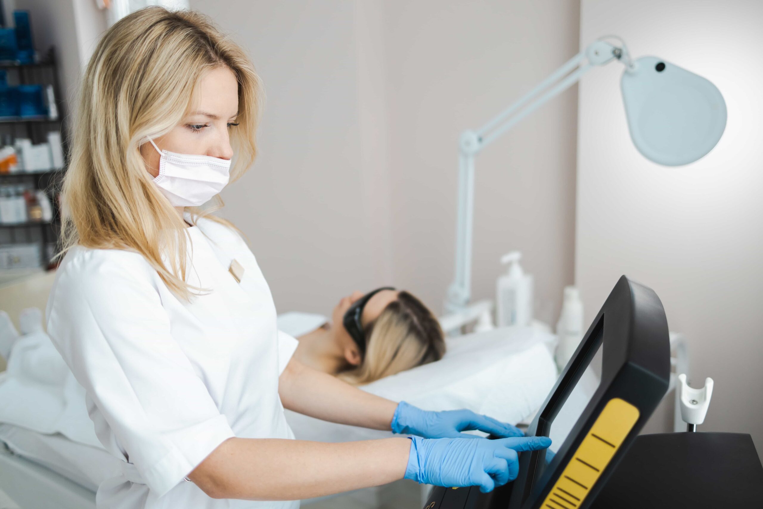 woman beautician in mask and medical uniform