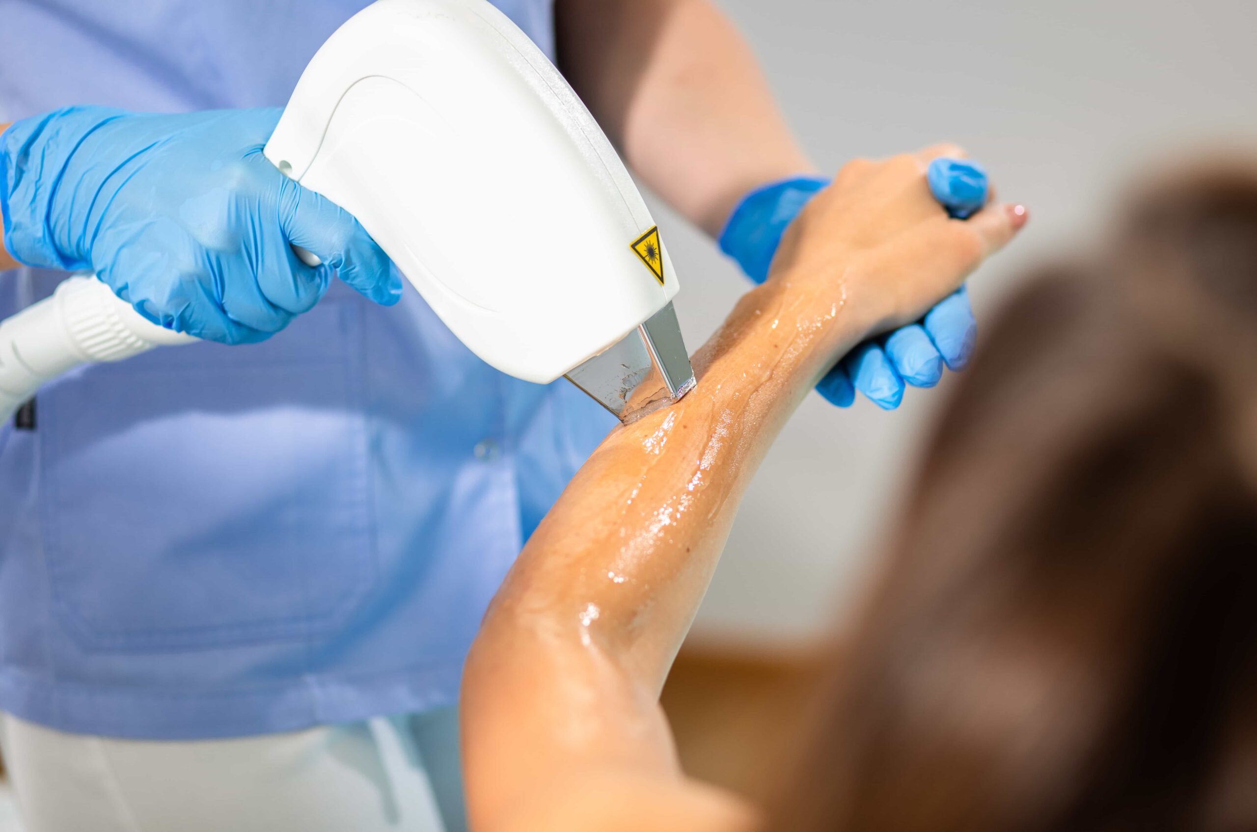 woman in a beauty salon removes hair from her arm