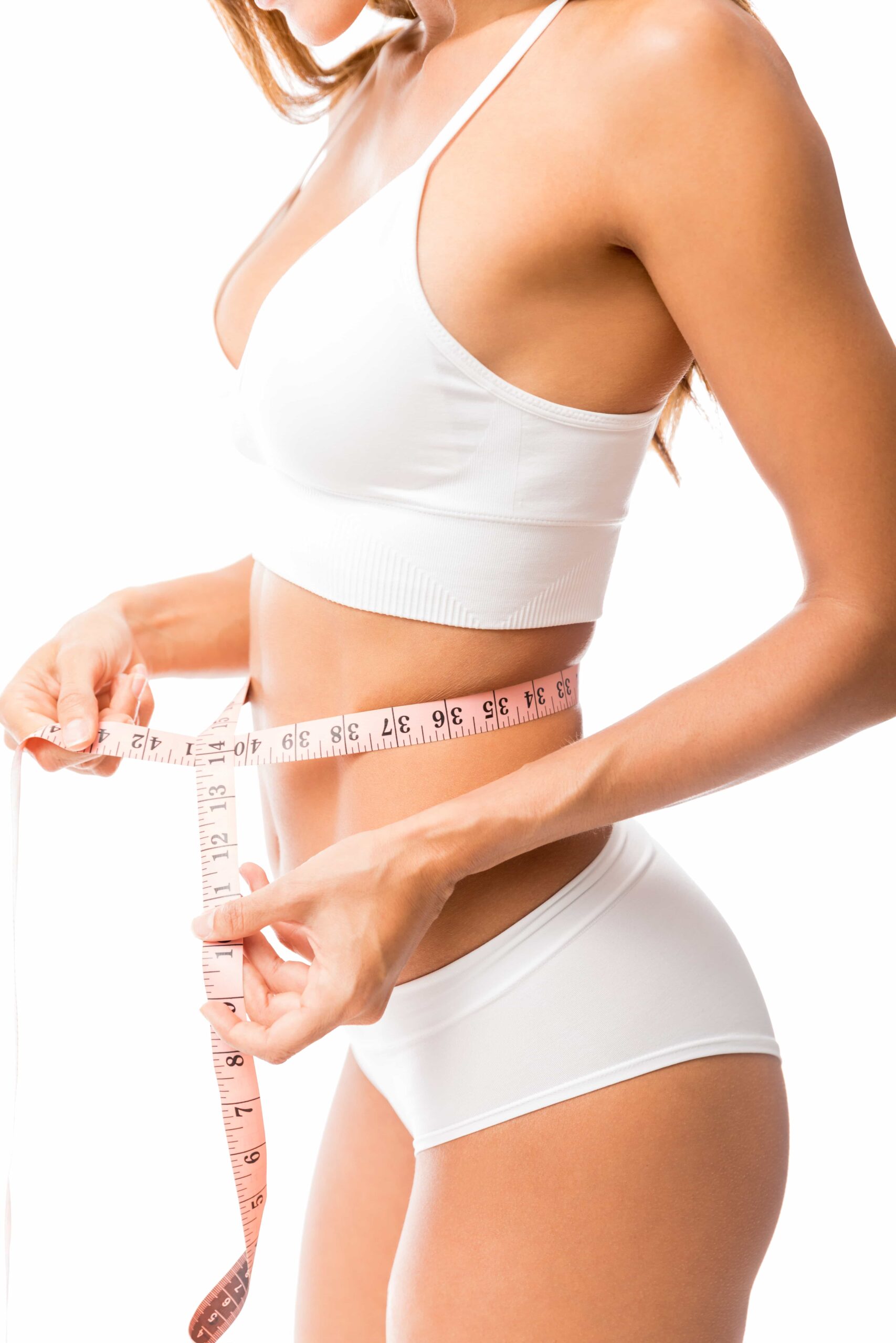 Profile view of a woman in a white sports bra and underwear measuring her waist with a pink measuring tape, symbolizing successful body contouring.