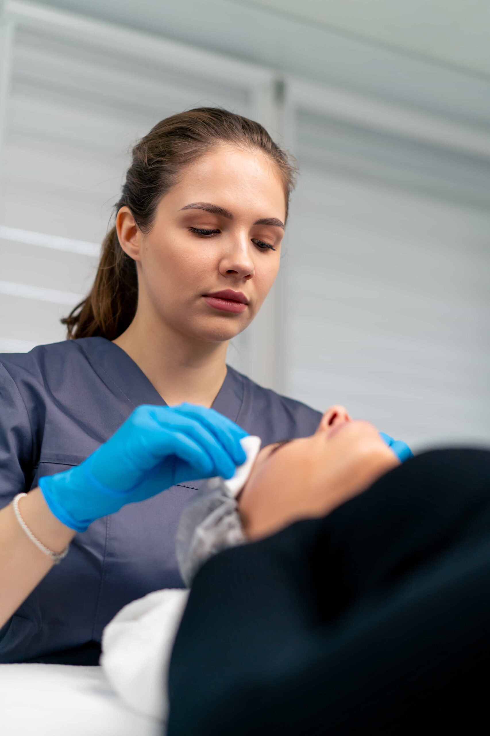 Doctor cleaning client's skin before treatment. 